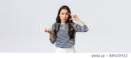 Lifestyle, people emotions and casual concept. Disappointed and annoyed young asian woman scold person making stupid mistake, roll finger over temple and raise hand in dismay 88420432