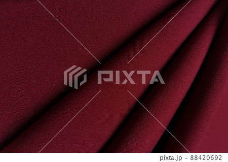 Red crumpled or wavy fabric texture background. Abstract linen cloth soft waves. Gabardine wool fabric. Merino yarn. Smooth elegant luxury cloth texture. Concept for banner or advertisement. Red crumpled or wavy fabric texture background. Abstract linen cloth soft waves. Gabardine wool fabric. Merino yarn. Smooth elegant luxury cloth texture. Concept for banner or advertisement. 88420692