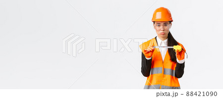 Disappointed gloomy female asian construction engineer, architect showing small size on tape measure, pouting upset with measurements, standing displeased in safety helmet, white background Disappointed gloomy female asian construction engineer, architect showing small size on tape measure, pouting upset with measurements, standing displeased in safety helmet, white background 88421090