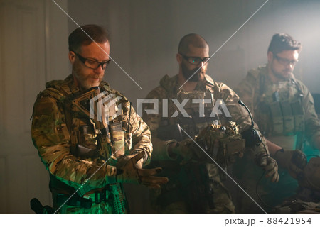 Bearded men in military equipment in dark room 88421954