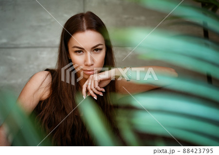 Woman portrait on a background of a gray wall through the leaves of a flower 88423795