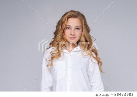 Caucasian girl, happy woman with blond long hair. In a white shirt. Makeup. 88423983