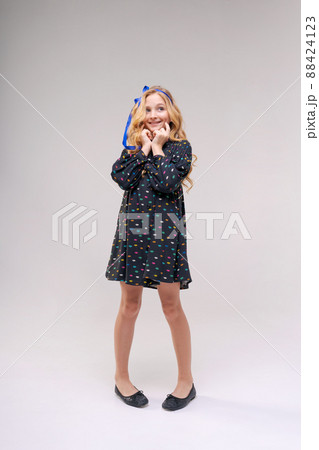 Photo of dreamy cute positive little girl with blond long wavy hair looking 88424123