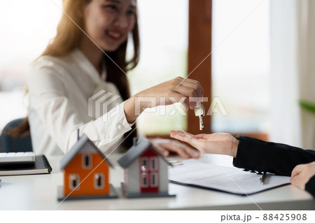 Real estate agent holding house key to his client after signing contract agreement in office,concept for real estate, moving home or renting property 88425908