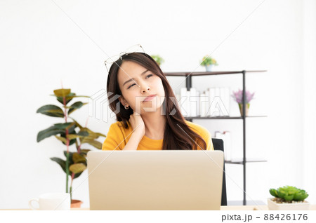 Young asian woman feeling pain in neck and shoulder after working on computer laptop for a long time Young asian woman feeling pain in neck and shoulder after working on computer laptop for a long time 88426176