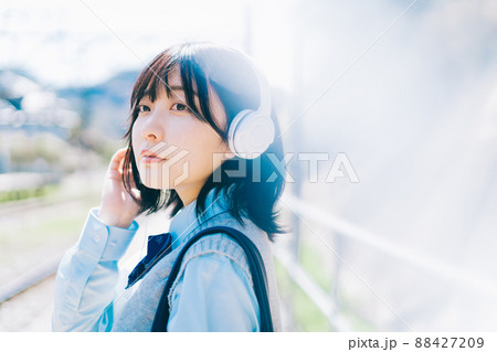 駅のホームで音楽を聴く女子高生 88427209