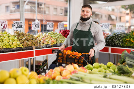 Man seller moving box of oranges in grocery shop 88427333