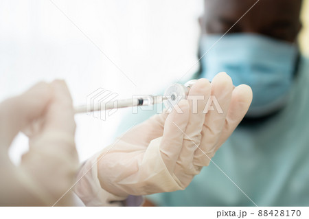 Selective focus of syringe, African American Wear a medical mask and being covid vaccinated for the prevention of coronavirus and flu. Concept of immunization from inoculation Selective focus of syringe, African American Wear a medical mask and being covid vaccinated for the prevention of coronavirus and flu. Concept of immunization from inoculation 88428170