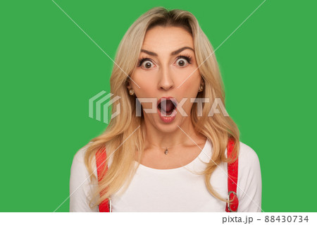 I can't believe this. Closeup portrait of funny amazed adult blond woman standing with wide open mouth and shouting in surprise, shocked expression. indoor studio shot isolated on green background I can't believe this. Closeup portrait of funny amazed adult blond woman standing with wide open mouth and shouting in surprise, shocked expression. indoor studio shot isolated on green background 88430734