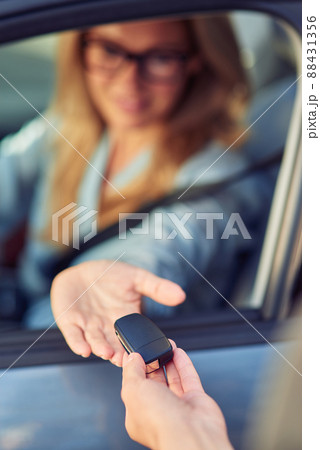 Male hand giving a car keys to woman sitting behind steering wheel, car purchase concept Male hand giving a car keys to woman sitting behind steering wheel, car purchase concept 88431356
