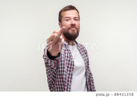 Portrait of impolite bully bearded man in casual plaid shirt showing middle finger fuck off gesture, aggressive hater expressing disrespect, protest. indoor studio shot isolated on white background 88431358