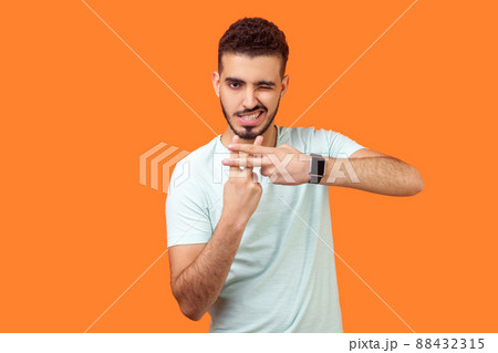 Hashtag. Portrait of joyous handsome brunette man with beard in casual white t-shirt making hash gesture and winking at camera, popular blog content. indoor studio shot isolated on orange background Hashtag. Portrait of joyous handsome brunette man with beard in casual white t-shirt making hash gesture and winking at camera, popular blog content. indoor studio shot isolated on orange background 88432315