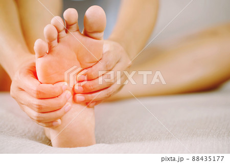A woman suffering from feeling knee pain sitting sofa at home. hand massaging her painful knee. Health care and medical concept. 88435177