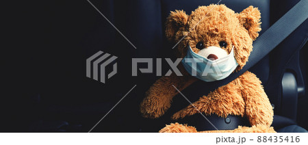 A brown teddy bear wearing a mask sits in the car. A brown teddy bear wearing a mask sits in the car. 88435416