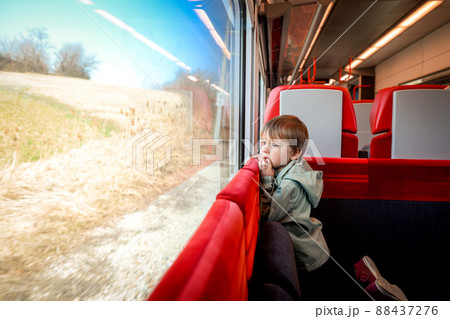Child traveling with family. Baby kid is looking in window. High speed express train. Travel by railway on vacation. Children in railroad car. Kids in rail way wagon. Entertainment for young passenger Child traveling with family. Baby kid is looking in window. High speed express train. Travel by railway on vacation. Children in railroad car. Kids in rail way wagon. Entertainment for young passenger 88437276