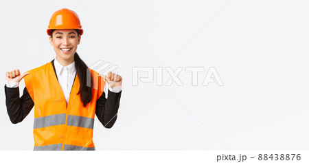 Successful proud smiling asian female construction manager, engineer in safety helmet pointing at herself, show-off. Architect recommend personal assistance, bragging accomplishments 88438876