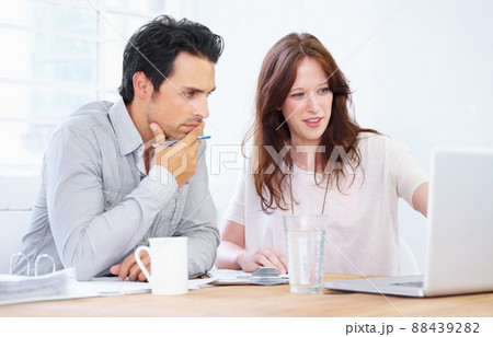 And this is why they call me the Queen of Spreadsheets.... Shot of a two young professionals sitting together and discussing something on a laptop. 88439282