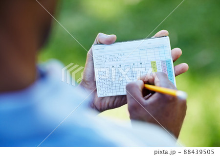 Staying below par. Rearview shot of a young golfer marking his scorecard. 88439505