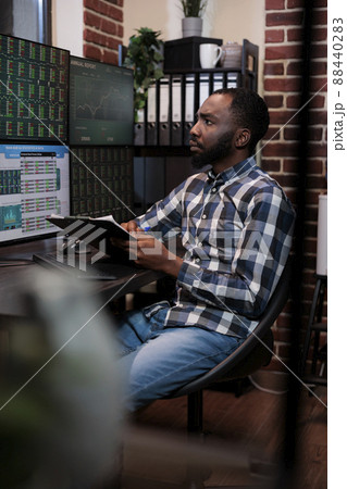 African american business man in investment agency office reviewing real time index charts. Hedge fund company professional trader reviewing financial data while analyzing market trend. 88440283