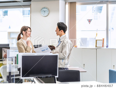 作業着を着た男性とスーツをオフィスカジュアルの女性 88446407
