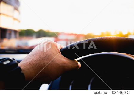 Driver's hand on the steering wheel inside of a car on road, a man driving a car in city Rush hour Traffic congestion Discomfort Drive at low-speed morning sun view. 88446939