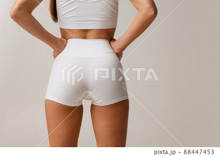 Sportive bottocks, legs. Cropped image of female body in white uderwear isolated over gray studio background 88447453