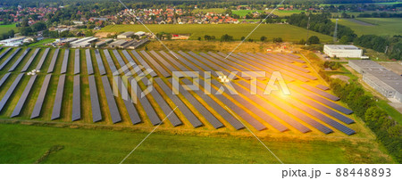 Aerial view of a large solar plant with solar panels and sun reflexions on the edge of a village in Germany Aerial view of a large solar plant with solar panels and sun reflexions on the edge of a village in Germany 88448893