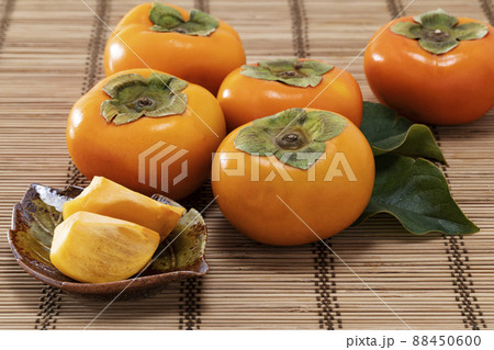 竹マットの上に葉を添えて並べた秋の味覚の柿 88450600