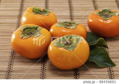 竹マットの上に葉を添えて並べた秋の味覚の柿 竹マットの上に葉を添えて並べた秋の味覚の柿 88450601