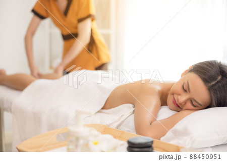 In a spa salon, a young woman enjoys massage therapy. 88450951