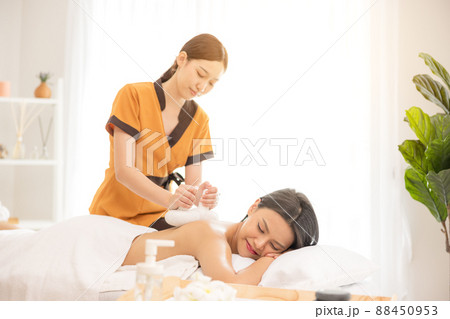 In a spa salon, a young woman enjoys massage therapy. 88450953