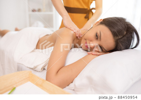 In a spa salon, a young woman enjoys massage therapy. In a spa salon, a young woman enjoys massage therapy. 88450954