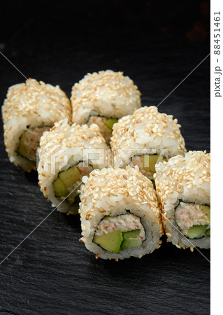Traditional delicious fresh sushi roll set on a black background. Sushi roll with rice, cream cheese, avocado, salmon, sesame. Philadelphia. Sushi menu. Japanese kitchen, restaurant. 88451461