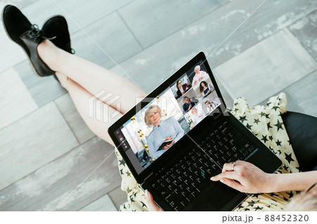 Web chat. Remote work. Virtual cooperation. Relaxed female freelancer using laptop discussing project with colleagues on screen in digital office with free space. 88452320