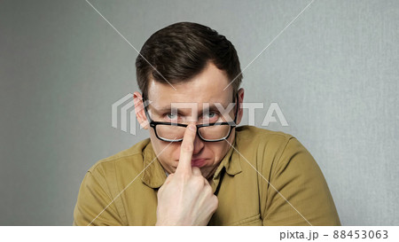 Emotional man with bad eyesight adjusts black-rimmed glasses Emotional man with bad eyesight adjusts black-rimmed glasses 88453063