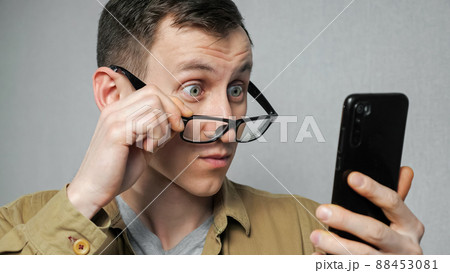 Man removes glasses after reading news on mobile phone 88453081
