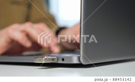 Man sits at table inserting USB device into port of laptop Man sits at table inserting USB device into port of laptop 88453142
