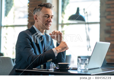 A mid aged businessman sitting at the laptop and thinking A mid aged businessman sitting at the laptop and thinking 88456239