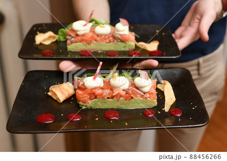 Waiter holding plates of salmon and guacamole Waiter holding plates of salmon and guacamole 88456266