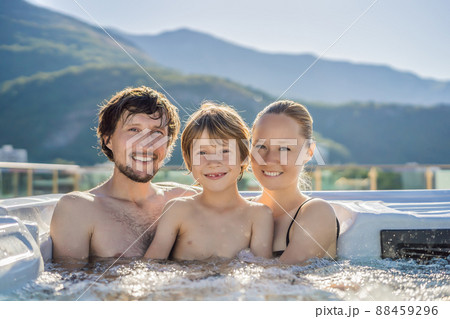 Portrait of young carefree happy smiling happy family relaxing at hot tub during enjoying happy traveling moment vacation. Life against the background of green big mountains 88459296