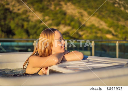 Portrait of young carefree happy smiling woman relaxing at hot tub during enjoying happy traveling moment vacation life against the background of green big mountains 88459324