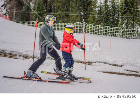 Boy learning to ski, training and listening to his ski instructor on the slope in winter 88459560