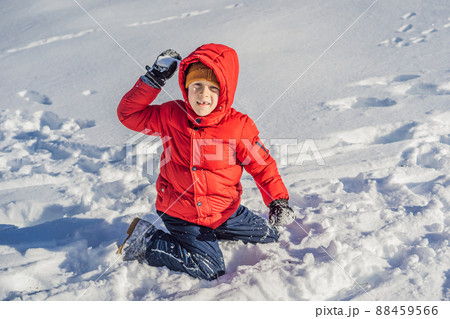 Funny little boy in blue winter clothes walks during a snowfall. Outdoors winter activities for kids. Cute child wearing a warm hat low over his eyes catching snowflakes with his tongue Funny little boy in blue winter clothes walks during a snowfall. Outdoors winter activities for kids. Cute child wearing a warm hat low over his eyes catching snowflakes with his tongue 88459566