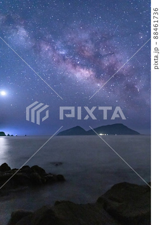 宮崎県日南市猪崎鼻から七つ岩と並ぶ大島の上に広がる星空に横に流れる天の川と灯台と共に海を照らす金星 88461736
