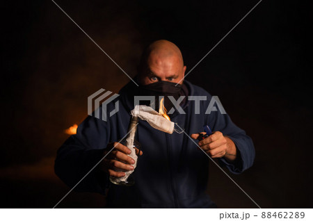 A masked man is holding a burning bottle. Molotov cocktail. A masked man is holding a burning bottle. Molotov cocktail. 88462289