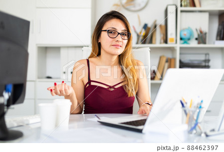 Young colombian woman in glasses working with laptop Young colombian woman in glasses working with laptop 88462397