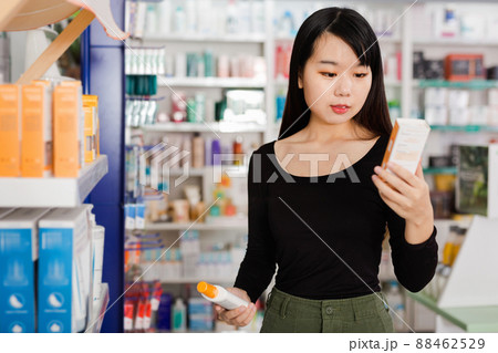 Young chinese female customer looking for right medicine in pharmaceutical store Young chinese female customer looking for right medicine in pharmaceutical store 88462529