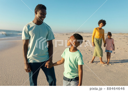 Happy african american father and son holding hands with mother and daughter in background at beach 88464646