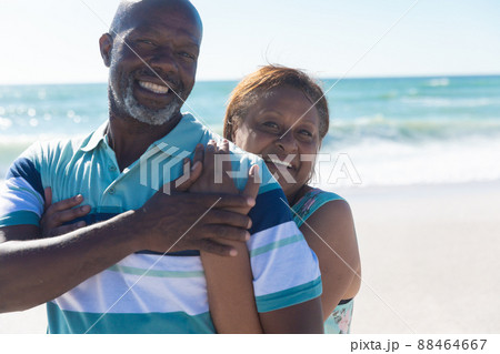 Portrait of happy retired african american senior couple standing together at beach on sunny day 88464667