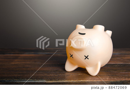 Dead piggy bank lies upside down. Economic depression. Financial crisis, end of savings, bankruptcy. Devaluation, inflation. Impoverishment. Refinancing restructuring of debts. 88472069